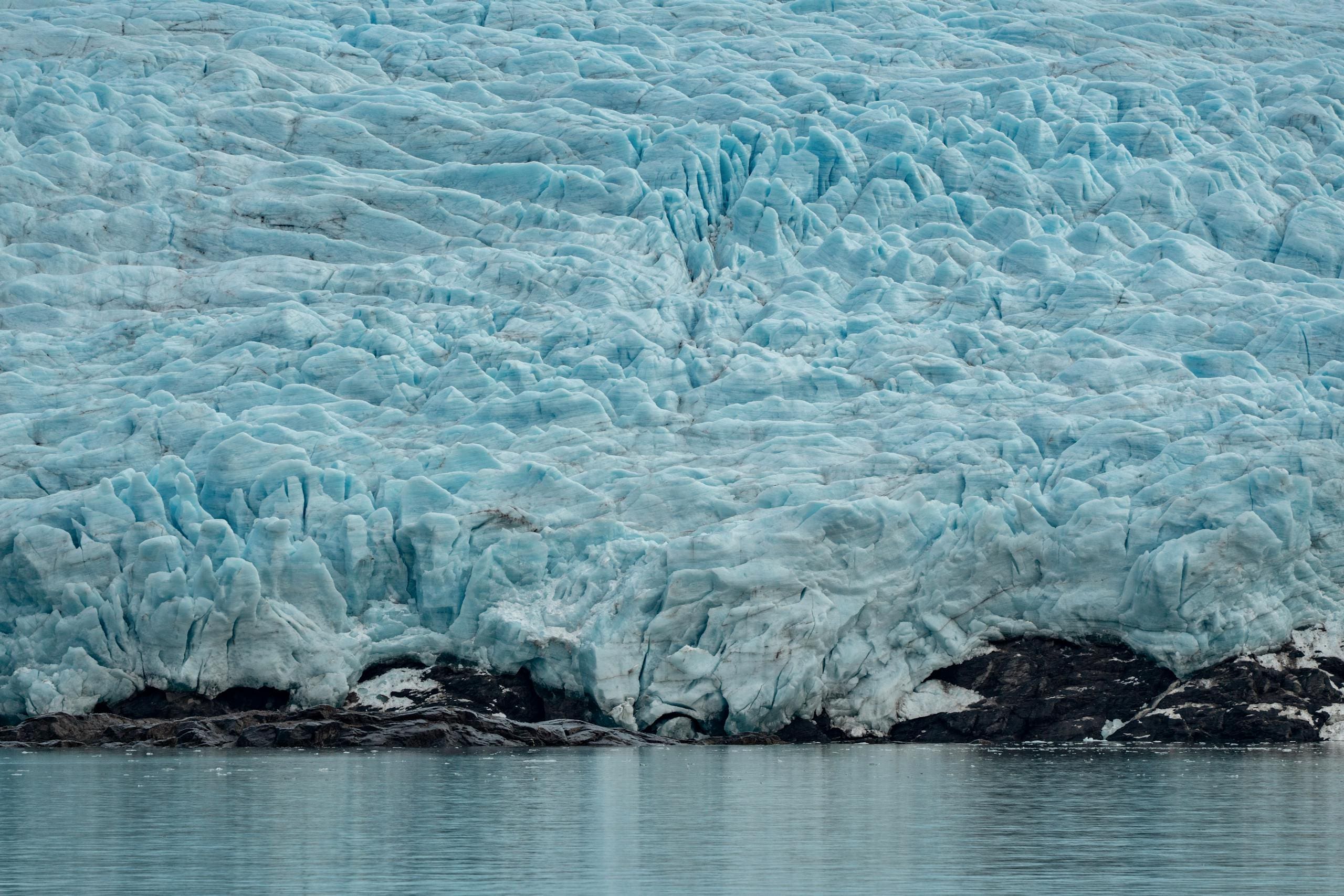 A detailed view of a grand glacier meeting a tranquil lake, showcasing nature's icy beauty.